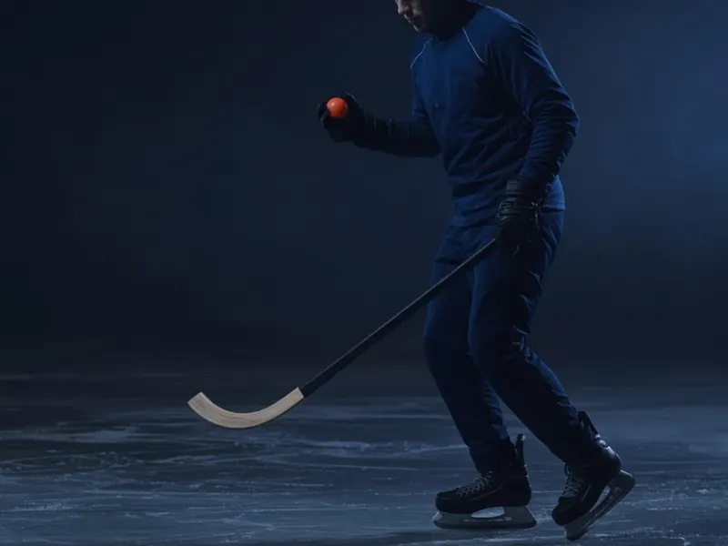 Bandyspieler mit Schläger und orangem Ball auf dem Eis